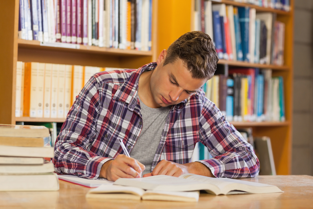 Handsome concentrated student studying his books in library