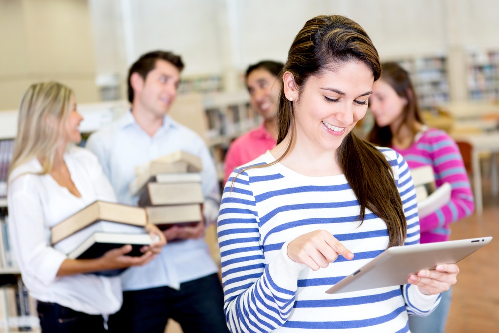 Woman with an e-book reader while friends carry books